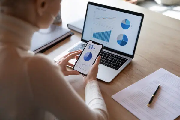 Woman,Hold,Smartphone,Use,Pc,At,Workplace.,Project,Stats,Financial Woman,Hold,Smartphone,Use,Pc,At,Workplace.,Project,Stats,Financial